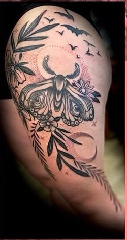 Blackwork moth, florals, and bats arm tattoo by Clayton